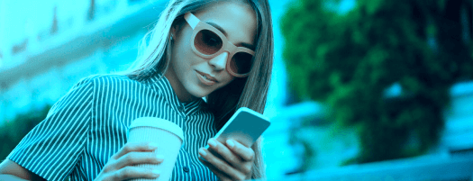 chica con café a la mano mirando el móvil